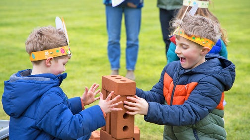 Children in Easter bunny ears stack bricks in a game at Blickling Estate